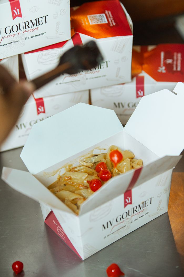 Gourmet takeout box with pasta and cherry tomatoes open on a kitchen counter.