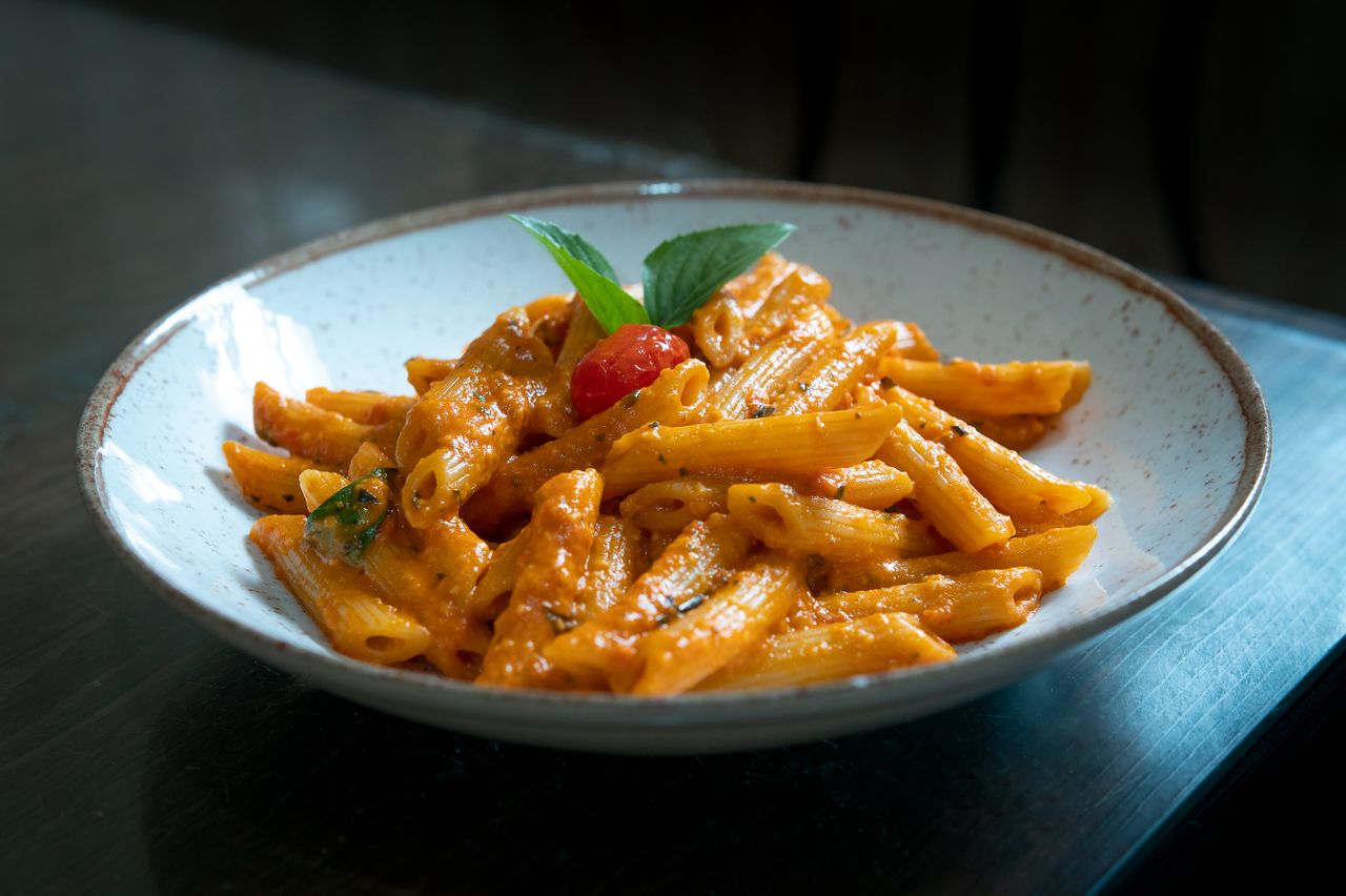 Penne pasta with rich tomato and basil sauce served in a rustic bowl.